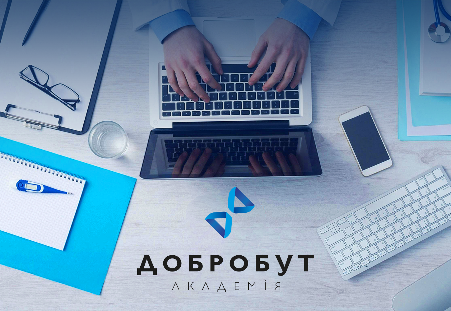 На фото зображений робочий стіл лікаря із документами, медичним обладнанням, ноутбуком та логотип Академії Добробут, який розробила команда True branding buro